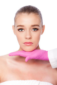 Cropped hands of doctor giving beauty treatment to young woman against white background