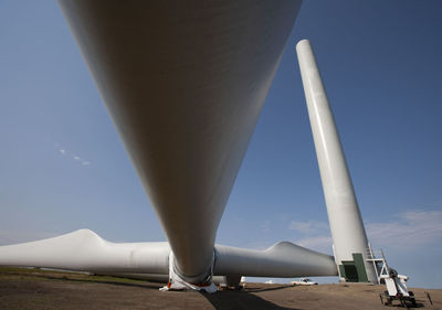 Wind turbines installing on field against clear blue sky during sunny day