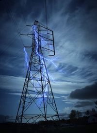 Low angle view of electricity pylon against lightning at dusk
