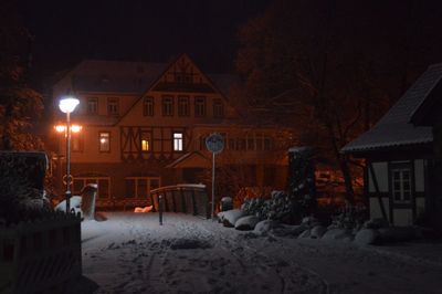 Illuminated street amidst buildings during winter at night