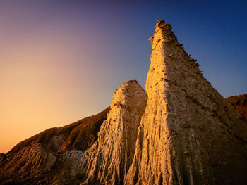 Low angle view of rock formations against sky during sunset