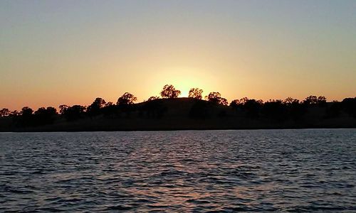 Scenic view of lake against clear sky during sunset