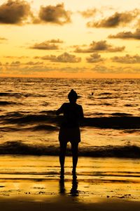 Silhouette man standing on beach against sky during sunset