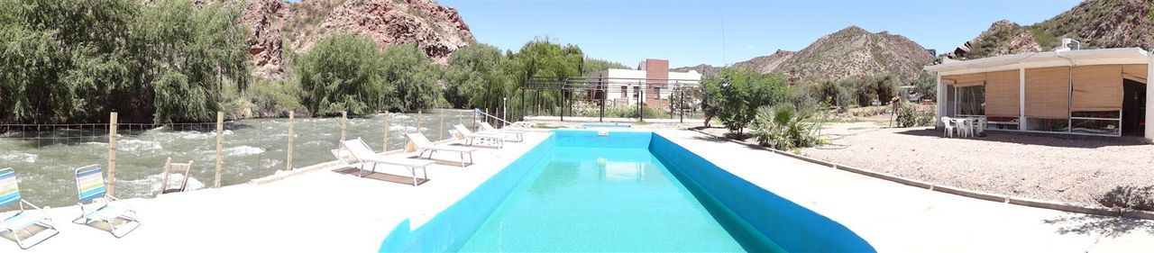 PANORAMIC VIEW OF SWIMMING POOL AGAINST TREES AND MOUNTAINS