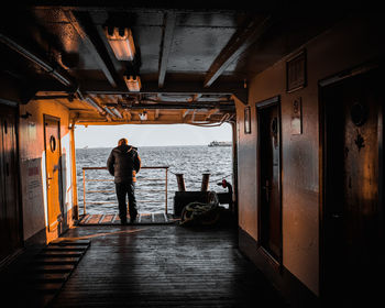 Rear view of man standing on boat in sea