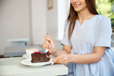 Midsection of woman holding ice cream on table