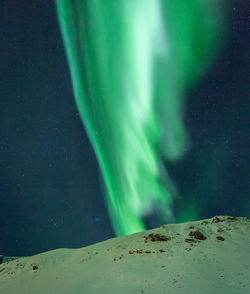 Low angle view of snow on land against sky at night