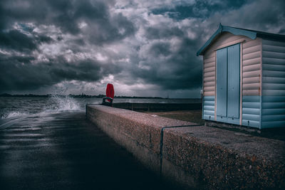 Building by sea against storm clouds