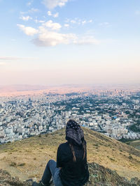 Girl standing in city against sky during sunset