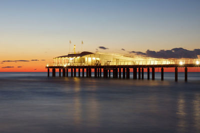 Pier over sea against sky during sunset