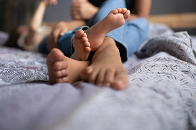 Low section of baby lying on bed at home
