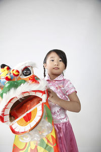 Cute girl holding dragon costume against white background