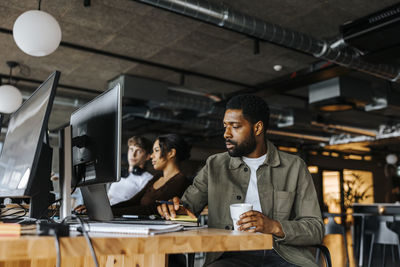Male computer programmer working while sitting at tech start up office