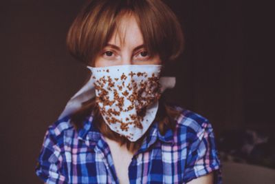 Portrait of teenage girl covering face against black background