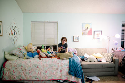 Teen girl with short hair sits on her bed looking at her phone