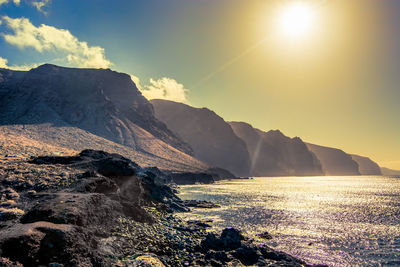 Scenic view of sea and mountains against sky during sunset