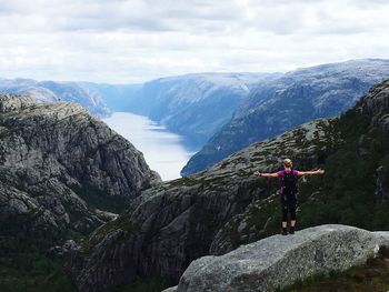 Woman standing on rock against sky