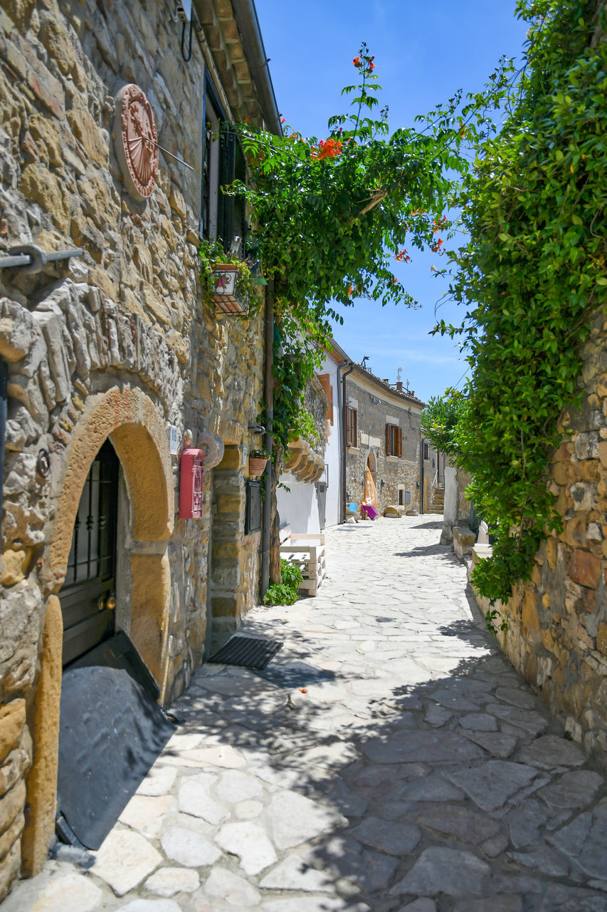 FOOTPATH AMIDST OLD BUILDINGS AGAINST SKY