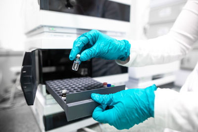 Midsection of scientist holding vial in laboratory