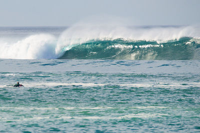 Scenic view of sea with person surfing against sky