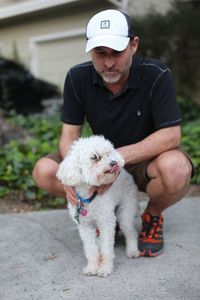 Portrait of man holding dog while sitting outdoors