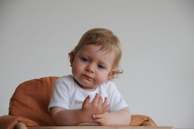 Portrait of cute boy sitting against white background