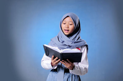 Portrait of a smiling young woman reading book