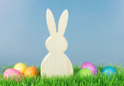 Close up of colorful easter eggs with decoration on grass against wall