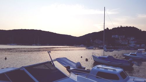 Sailboats moored on sea against sky during sunset