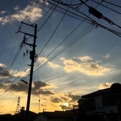 Low angle view of silhouette power lines against sky