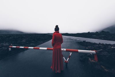 Rear view of woman standing on mountain against sky