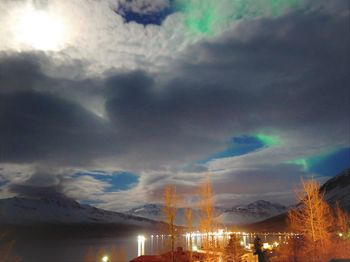 Illuminated cityscape against cloudy sky