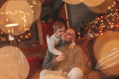 Candid authentic happy dad playing with little son fooling around at wooden lodge xmas decorated