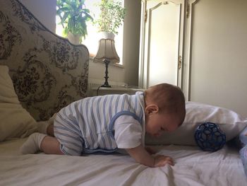 Cute baby boy crawling on bed at home