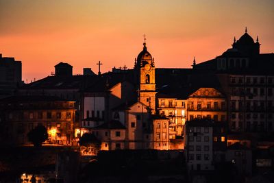 Buildings in town against sky at sunset