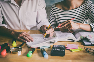 Midsection of friends studying on desk