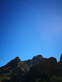 Low angle view of mountains against clear blue sky