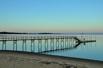 Pier over sea against clear blue sky