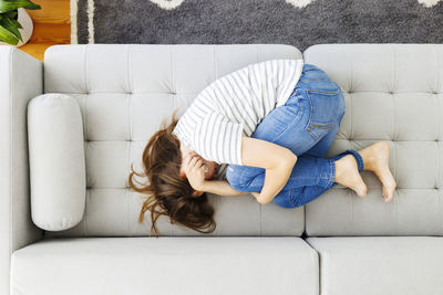 Full length of woman sitting on sofa at home