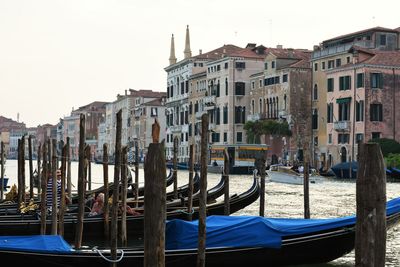 Boats moored in canal against buildings in city