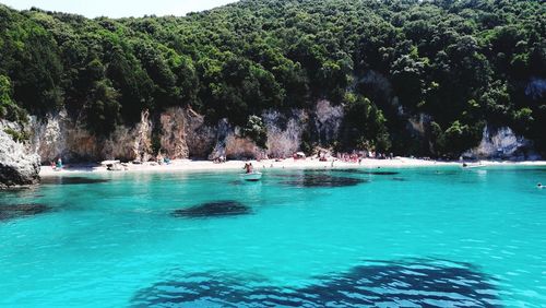 People swimming in pool by sea against sky
