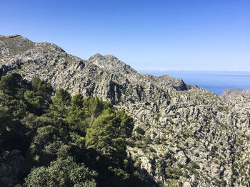 Scenic view of cliff by sea against clear sky