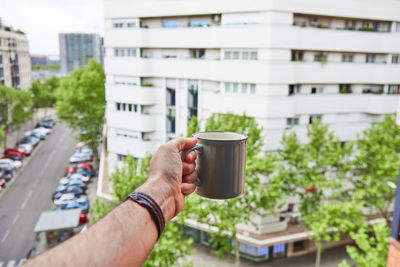Man holding coffee cup and buildings in city