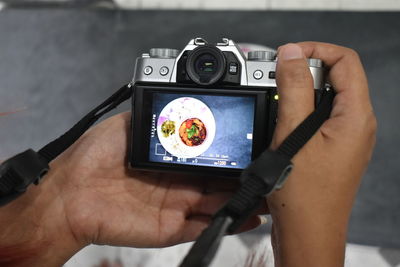 Cropped hand of man holding camera