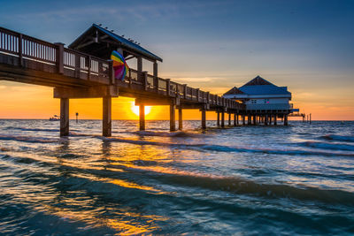 Pier over sea against sky during sunset