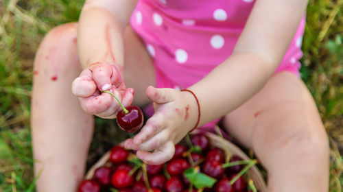 Midsection of baby girl holding cherry