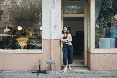 Portrait of confident female craftsperson standing at workshop entrance