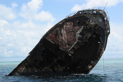 Abandoned boat in sea against sky