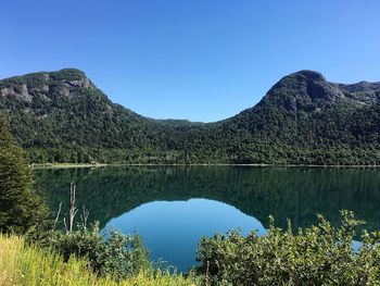 Scenic view of lake and mountains against clear blue sky