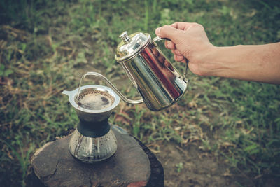 Cropped hand pouring water in coffee maker on table